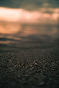 Surface level of beach against sky during sunset