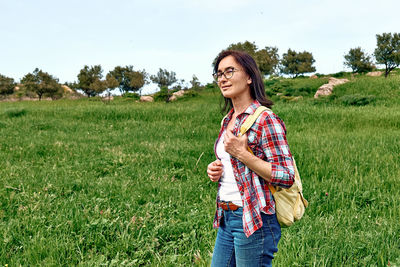 Happy beautiful carefree woman walking on a spring meadow with green grass. hiking outdoors