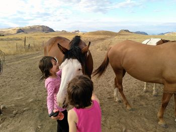 Girls standing by horses on sand