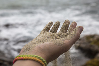 Close-up of hand holding sand at beach