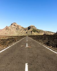 Empty road in desert against clear blue sky