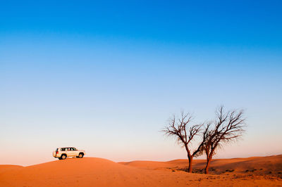 Scenic view of desert against clear blue sky and one car on sand dune for desert safari drive