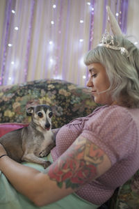 Young woman wearing bunny ears holding a dog