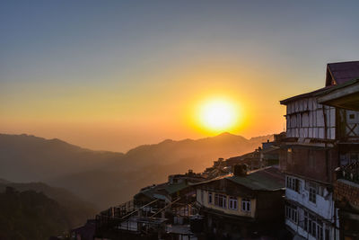 Buildings in town against sky during sunset