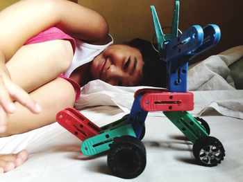 Portrait of girl with toy lying on bed at home