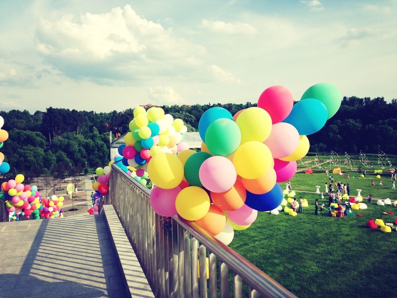 multi colored, sky, balloon, colorful, cloud - sky, flower, variation, railing, in a row, blue, day, outdoors, leisure activity, abundance, cloud, nature, celebration, large group of objects, tree