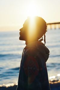 Side view of man looking at sea during sunset