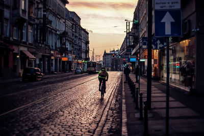 Rear view of man cycling on road during sunset