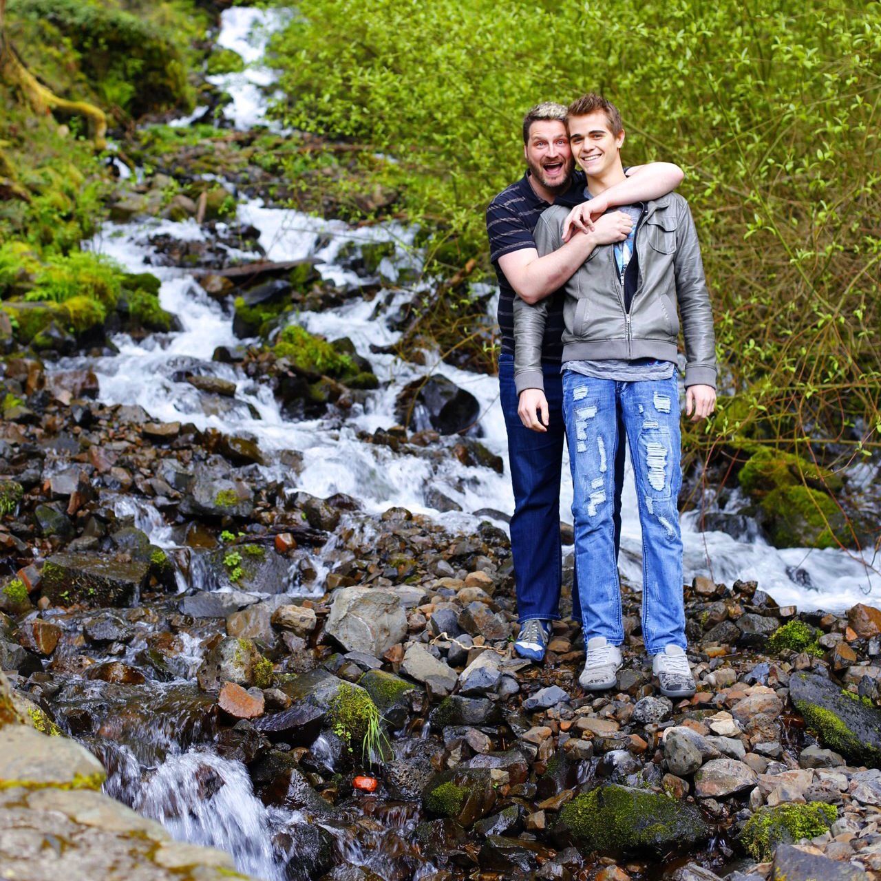 lifestyles, leisure activity, casual clothing, person, young adult, full length, rock - object, standing, young men, water, front view, looking at camera, portrait, smiling, nature, three quarter length, forest