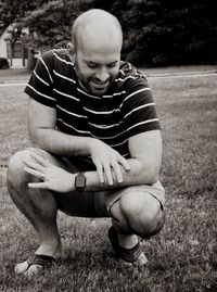 Full length of smiling man crouching on field