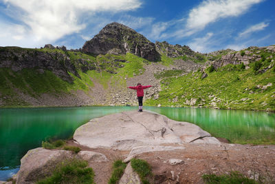 Little girl looking with open arms at the bombasel lake in the dolomites of trentino