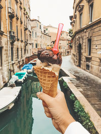 Cropped image of hand holding ice cream in city