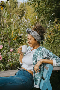 Female environmentalist with coffee cup laughing in community garden