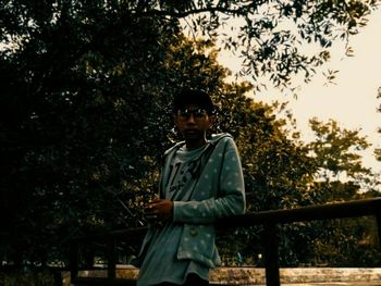 Portrait of young man standing against trees