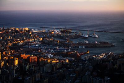 High angle view of illuminated city by sea against sky