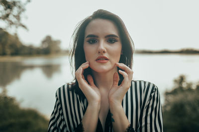 Portrait of young woman standing against lake
