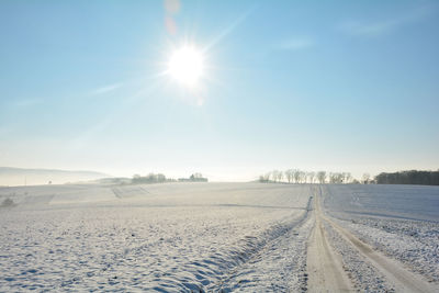 Snow-covered road in winter in the countryside with sun in spessart, bavaria, germany