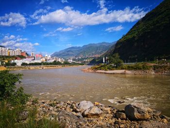 Scenic view of river by buildings against sky