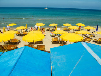 Beach umbrellas by sea against blue sky