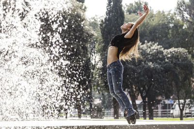 Full length of woman dancing against trees