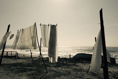 Clothes hanging from string on sea shore against sky