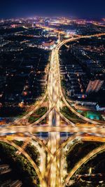 High angle view of light trails on road amidst buildings in city at night
