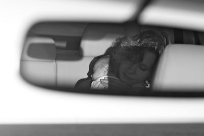 Reflection of mother and sleeping daughter seen in rear-view mirror