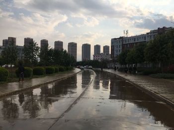 Canal amidst buildings in city during sunset