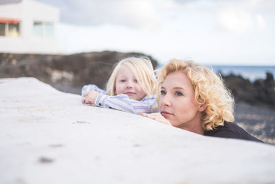Mother and son leaning on sand at beach