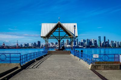 Jetty at riverside with city skyline in background