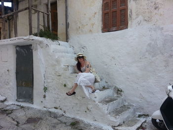 Young woman sitting on steps outside old house