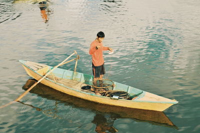 High angle view of fisherman standing in boat on lake