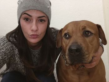 Portrait of young woman with dog at home