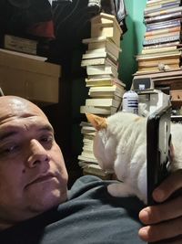 Portrait of man with cat sitting on books