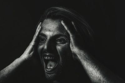 Young woman screaming over black background