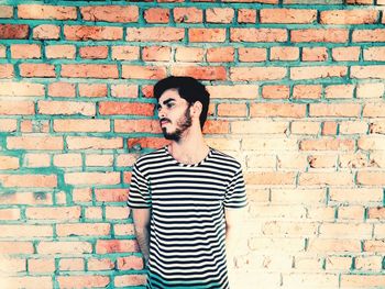 Man standing against brick wall