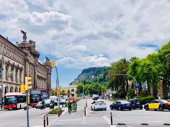 Traffic on city street against cloudy sky