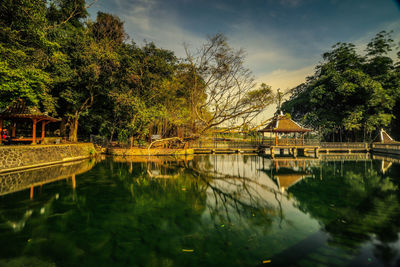 Scenic view of lake by trees and building against sky