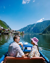 Man sitting on boat in lake against sky