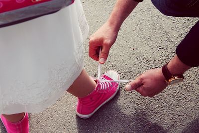 Father tying daughters shoe on street