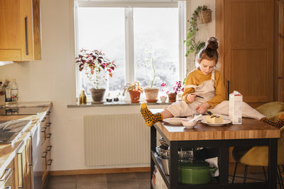 Girl sitting on table with cooking ingredients