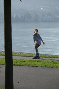 Woman inline skating on road by sea