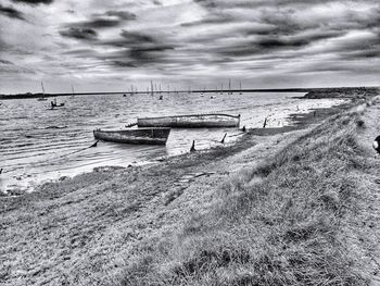 Sailboats moored on beach against sky