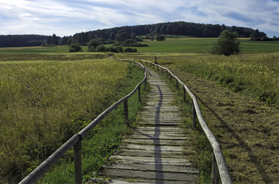 Boardwalk amidst field against sky