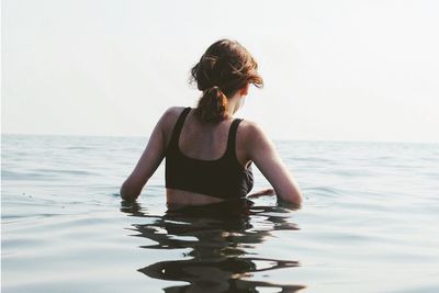 Woman in sea against sky