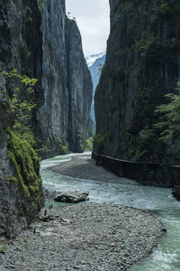 Stream flowing amidst mountains against sky