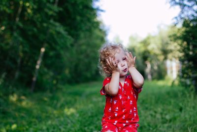 Girl standing on field against trees