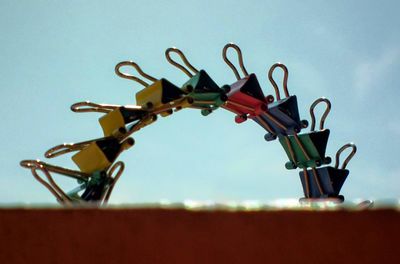 Colorful paper clips against sky