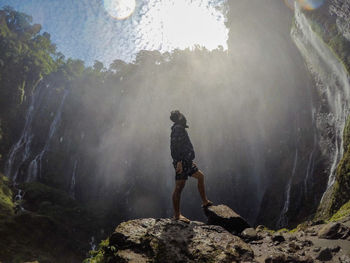 Low angle of man looking away standing by waterfall