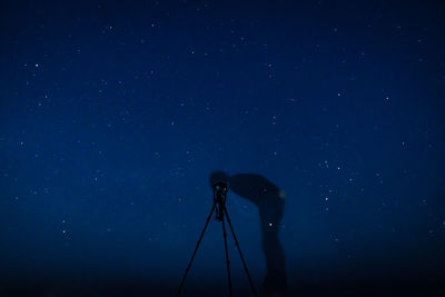 Silhouette man photographing against blue sky at night